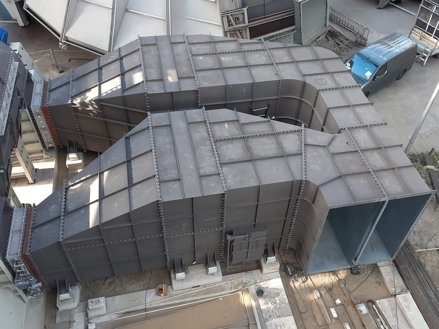 Großdimensionierte geschweißte Luftkanal‑Konstruktion aus Metall mit mehreren gebogenen Segmenten und Verstärkungsstrukturen, von oben aufgenommen.